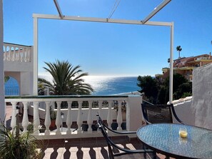 Ein Balkon mit Meerblick, ein Tisch mit einem Glas und ein Stuhl.