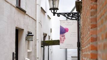 A narrow street with a building featuring a sign for 'Au Chateau Gris' with a floral design.
