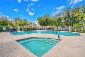 Une piscine rectangulaire dotée d’un plongeoir, entourée d’une clôture et d’arbres.