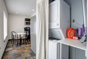 A compact kitchen with a dining area, a washing machine, and a small table with chairs. - Cozy 1-bedroom bungalow in historic North End of Boise with AC and sauna (Boise)