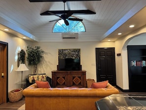 A living room with a sofa, a television, a ceiling fan, and a bookshelf. - Cozy 1-bedroom bungalow in historic North End of Boise with AC and sauna (Boise)