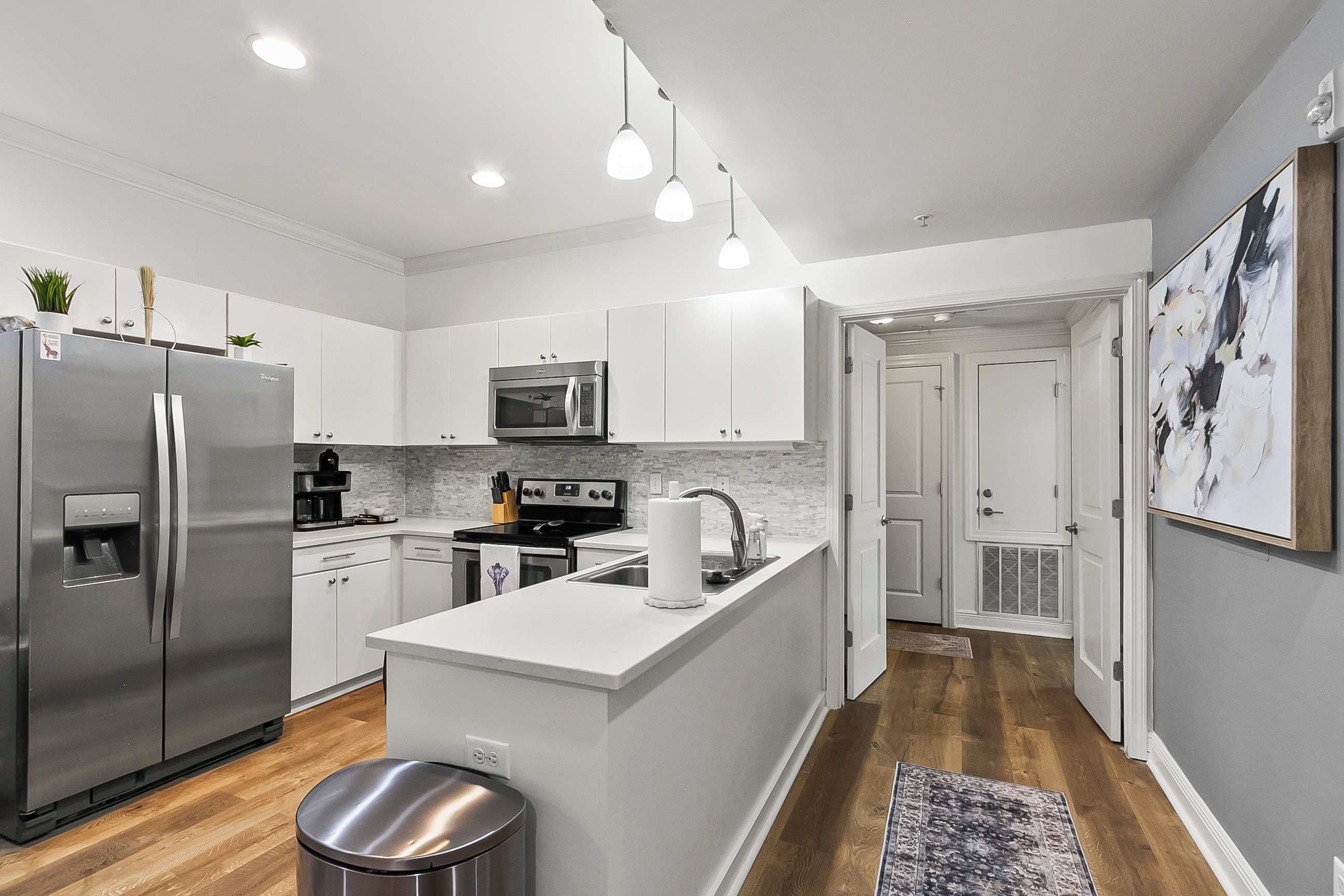 A modern kitchen with stainless steel appliances, white cabinetry, and a central island.