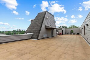 A rooftop terrace with a sloped roof, a covered seating area, and a view of the sky. - HiTide Condo | Walk to Campus | Prime Gameday Unit (Tuscaloosa)