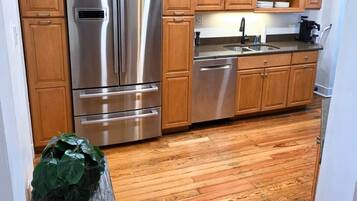 Une cuisine avec des meubles en bois, des appareils électroménagers en acier inoxydable et un plancher en bois.