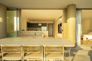 A modern dining area with a large table and wicker chairs, leading to a kitchen and living space. - Oceanfront Sunsets and Private Pool in Playa Blanca (Playa Blanca)
