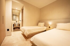 A hotel room with two beds, a bathroom with a mirror, and a nightstand with a lamp. - Oceanfront Sunsets and Private Pool in Playa Blanca (Playa Blanca)