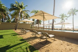 A beachside lounge with sun loungers and umbrellas, a pool, and palm trees. - Oceanfront Sunsets and Private Pool in Playa Blanca (Playa Blanca)