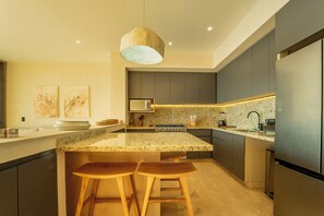A modern kitchen with granite countertops, dark cabinetry, and a central island with bar stools. - Oceanfront Sunsets and Private Pool in Playa Blanca (Playa Blanca)