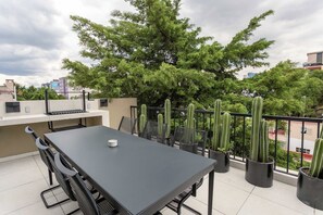 A rooftop terrace with a dining table, chairs, and potted cacti. - Studio Siqueiros: with Queen Bed, Workspace & Rooftop Access (Ciudad de México)