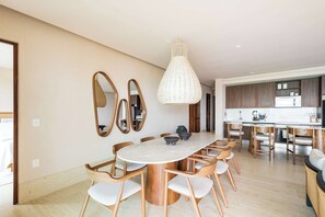 A modern dining area with a round table, wooden chairs, and a hanging light fixture. - Artila Isla Mujeres: The Ocean Dream Sanctuary (Isla Mujeres)