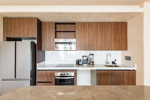 A modern kitchen with wooden cabinets, stainless steel appliances, and a marble countertop. - Artila Isla Mujeres: The Ocean Dream Sanctuary (Isla Mujeres)