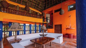 Um quarto espaçoso com teto alto, um banco de madeira, um sofá branco e uma mesa pequena.