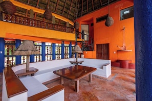 A spacious room with a high ceiling, a wooden bench, a white sofa, and a small table. - Bella Mar: Ocean Front w/ Pool Views (Isla Mujeres)