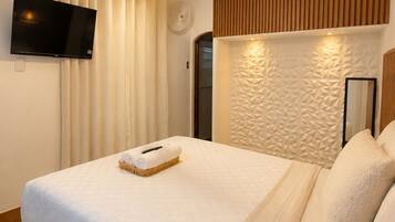 A hotel room with a bed, a flat-screen TV, a wall-mounted light fixture, and a textured wall panel.