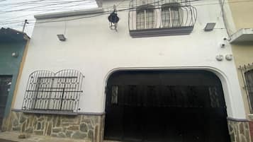 Un edificio con un amplio portón de garaje, base de piedra y barandilla metálica en el nivel superior.