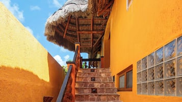 Una escalera conduce a un edificio con techo de paja y una ventana con vidrieras decorativas.