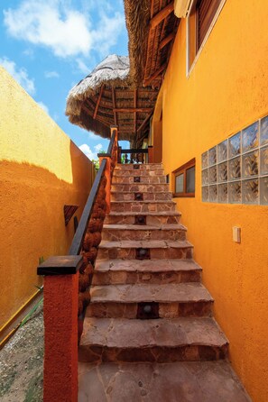 A staircase leading to a building with a thatched roof and a window with decorative glass. - Bella Mar: Ocean Front w/ Pool Views (Isla Mujeres)