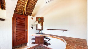 Um banheiro com porta de madeira, porta-toalhas, espelho e piso de ladrilho.