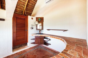 A bathroom with a wooden door, a towel rack, a mirror, and a stone-tiled floor. - Bella Mar: Ocean Front w/ Pool Views (Isla Mujeres)
