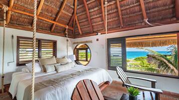 Ein Zimmer mit Bett, Stuhl und Blick auf den Ozean.