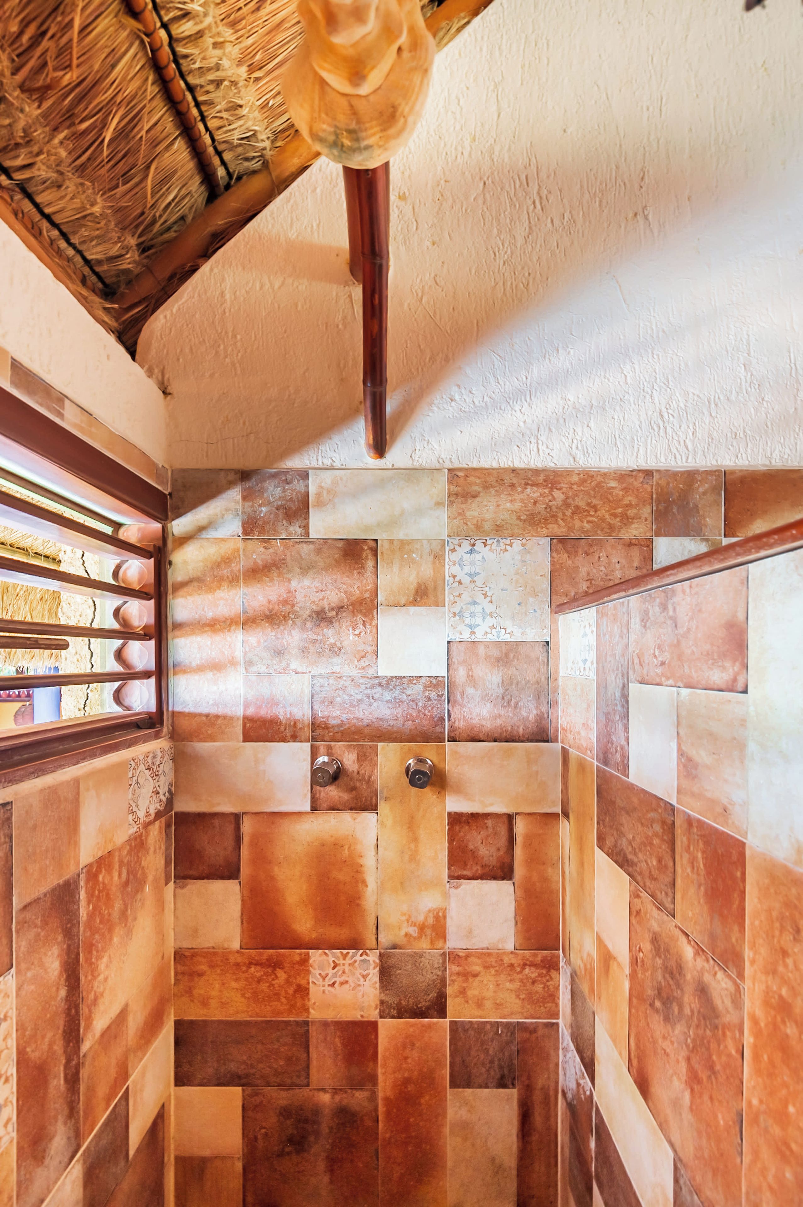 A bathroom with a tiled wall and a wooden ceiling.