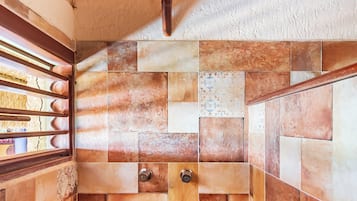 A bathroom with a tiled wall and a wooden ceiling.