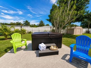 A patio area with a hot tub, two Adirondack chairs, and a small table with towels and candles. - New Hot Tub Retreat, Just 6 Miles to Siesta Key (Sarasota)