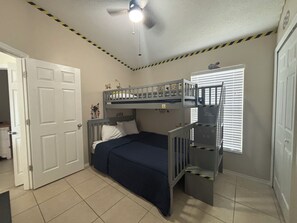 Ein Schlafzimmer mit Etagenbett, Deckenventilator und einem Fenster mit Jalousien.
