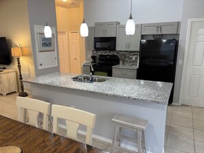 A kitchen with granite countertops, stainless steel appliances, and pendant lighting. - Welcome to Maysons Cozy Nest, a comfortable 3 bedroom home in Kissimmee, Fl. (Kissimmee)