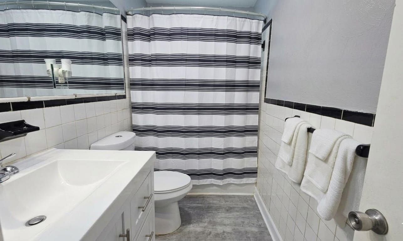 Un baño con lavamanos blanco, inodoro y cortina de ducha.