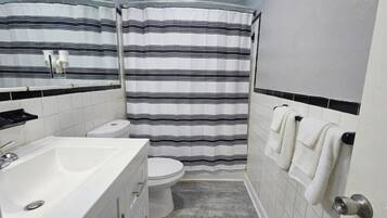 Un baño con lavamanos blanco, inodoro y cortina de ducha.