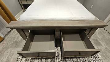 Un dormitorio con cama, dos cajones y piso alfombrado.