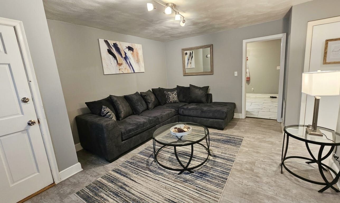 Ein Wohnzimmer mit einem Ecksofa, einem Couchtisch und einem Teppich.