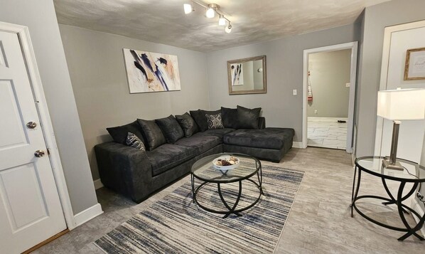 Ein Wohnzimmer mit einem Ecksofa, einem Couchtisch und einem Teppich.
