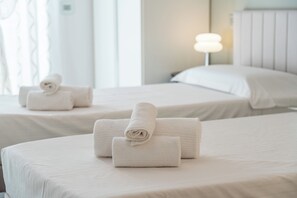 Habitación de hotel con dos camas, cada una con una toalla blanca doblada con cuidado.