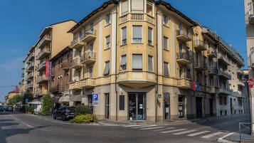 Un edificio de varios pisos con entrada en esquina, un letrero de estacionamiento visible y una señal de parada.