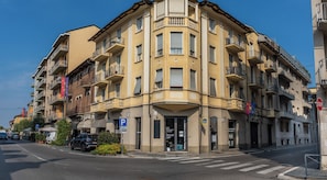 Un edificio de varios pisos con entrada en esquina, un letrero de estacionamiento visible y una señal de parada.