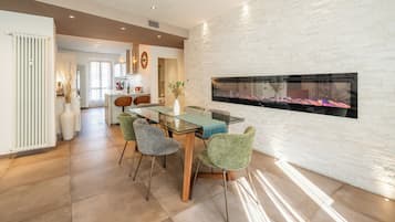 Una cocina moderna con comedor, que incluye una mesa de vidrio, sillas tapizadas en verde y una chimenea empotrada.
