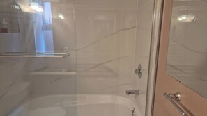 A bathroom with a glass shower enclosure, a bathtub, and a mirror. - Garden suite by DSOUZA (Vancouver)
