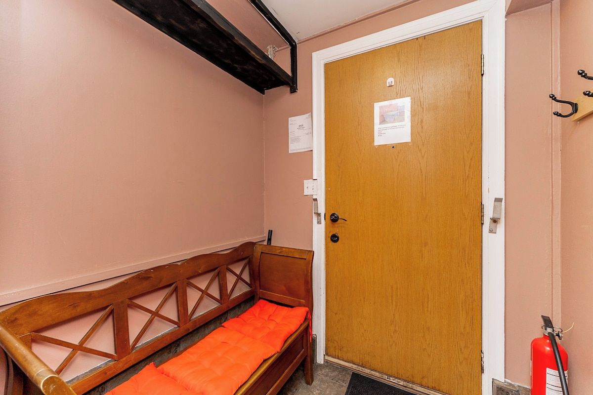 A room with a wooden bench, a door with a notice, and a fire extinguisher.
