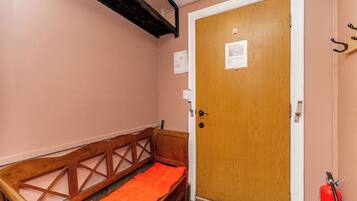 A room with a wooden bench, a door with a notice, and a fire extinguisher.