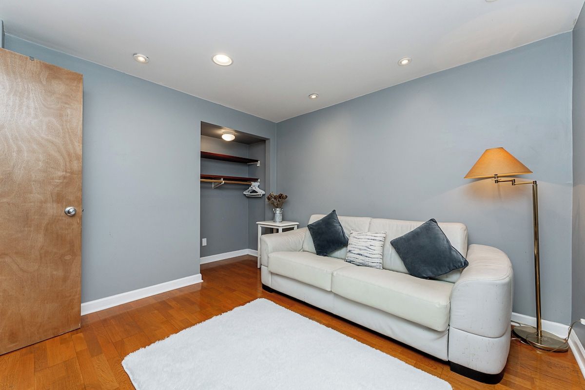 A room with a white sofa, a floor lamp, and a wooden door.