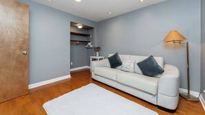 A room with a white sofa, a floor lamp, and a wooden door. - Garden suite by DSOUZA (Vancouver)