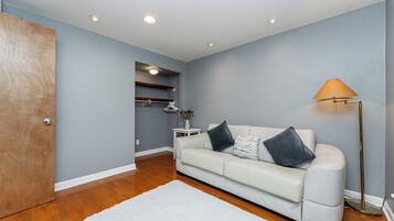 A room with a white sofa, a floor lamp, and a wooden door.