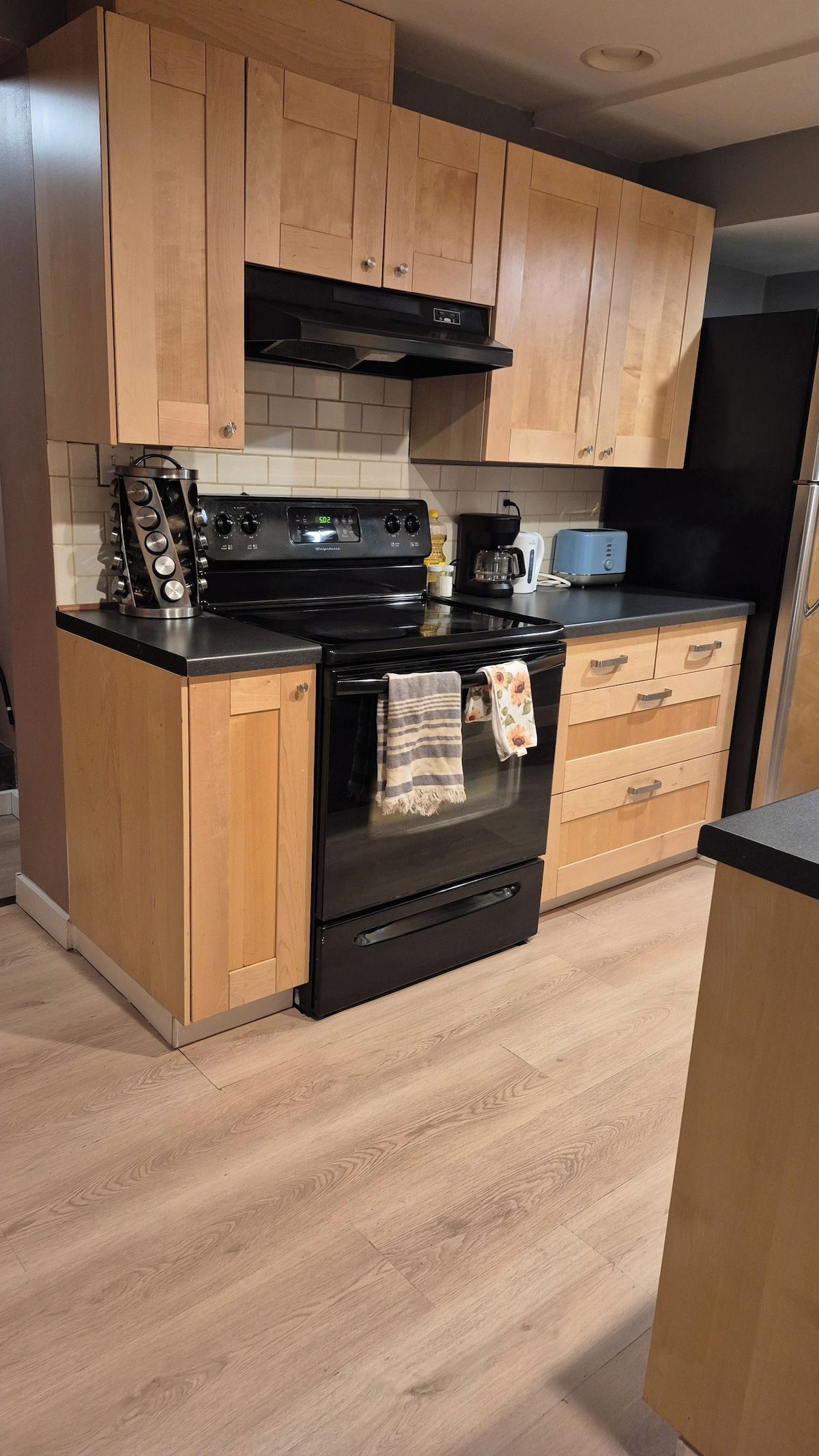 A kitchen with wooden cabinets, a black stove, and a tiled backsplash.