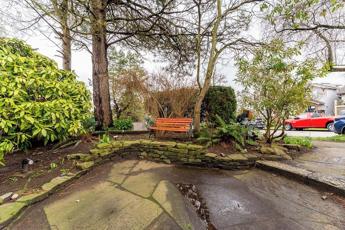 A stone bench in a garden area with a stone wall and a small water feature.