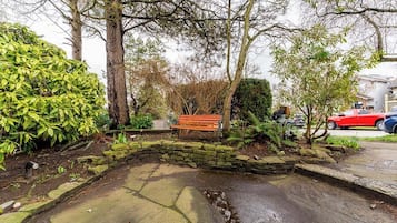 A stone bench in a garden area with a stone wall and a small water feature.