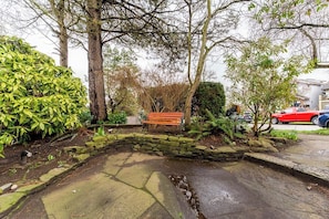 A stone bench in a garden area with a stone wall and a small water feature.