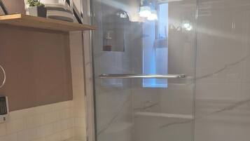 A modern bathroom with a glass-enclosed shower, a white toilet, and a wooden vanity with a sink.