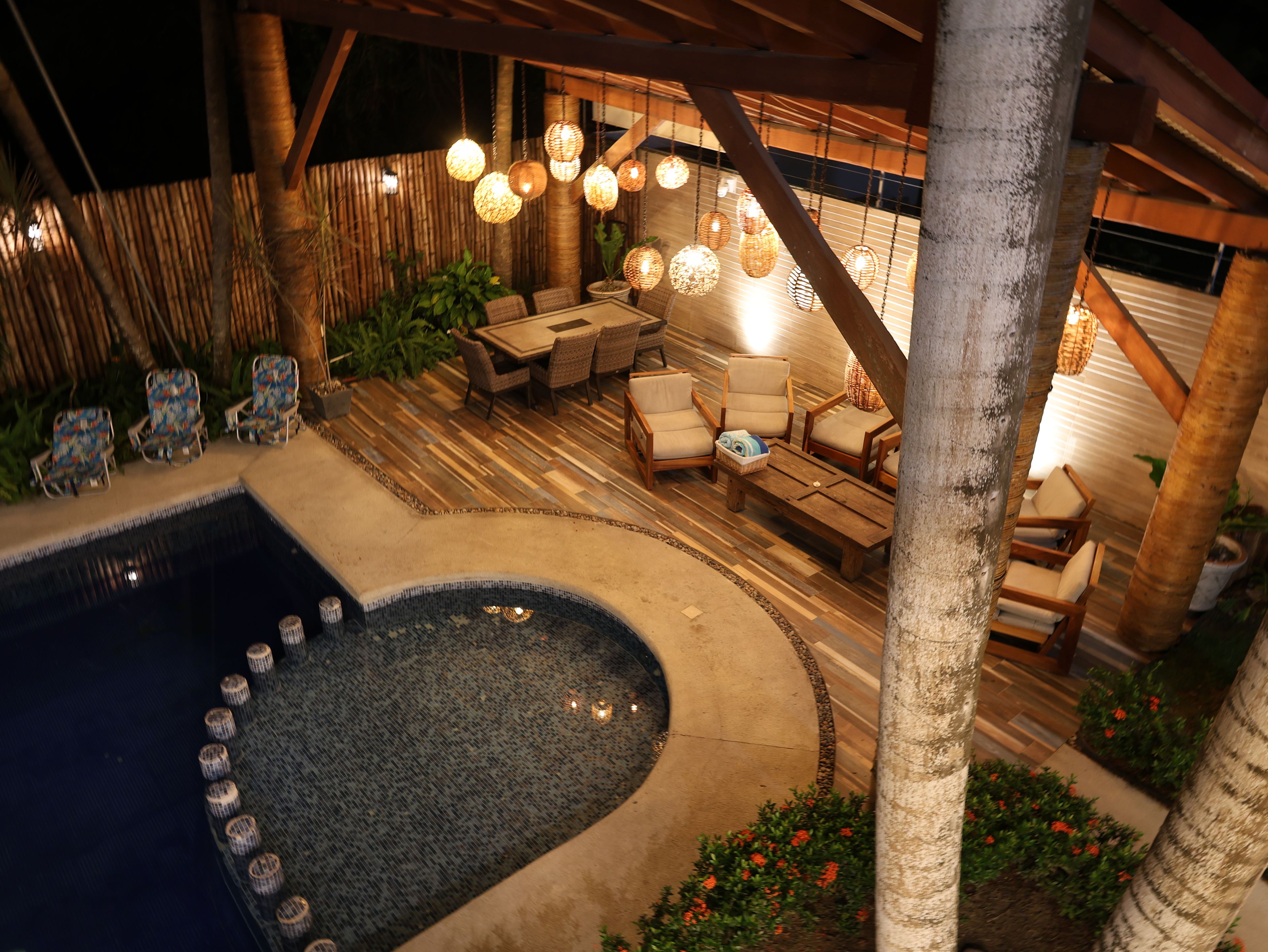A pool area with a hot tub, lounge chairs, and hanging lights.